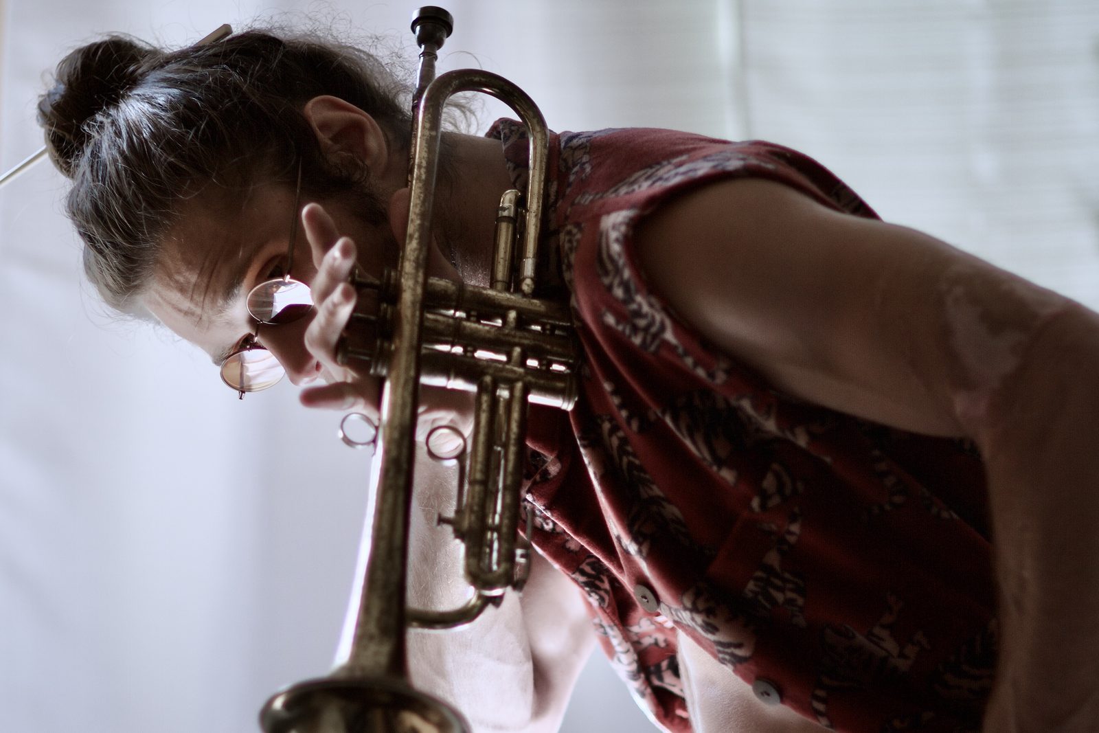 Close portrait of Jamen Krause raising a trumpet toward the camera.